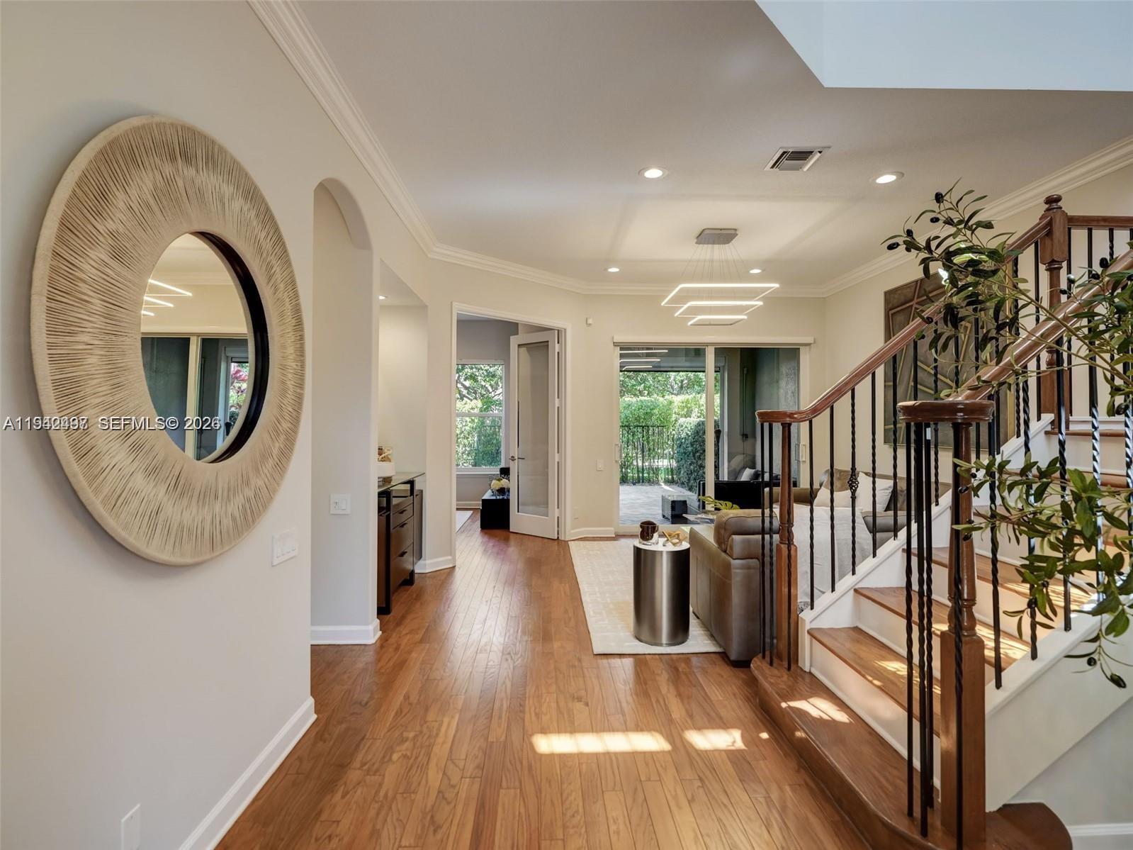 An entryway with hardwood floors, a round mirror, and a staircase leading to a living area — 963 S Harbor Vw S, Hollywood FL 33019, HOLLYWOOD, FL