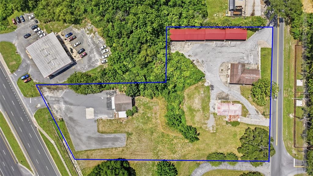 This aerial view shows a commercial property with multiple buildings, parking areas, and surrounding vegetation — 2766 US HIGHWAY 441/27 HIGHWAY, FRUITLAND PARK, FL
