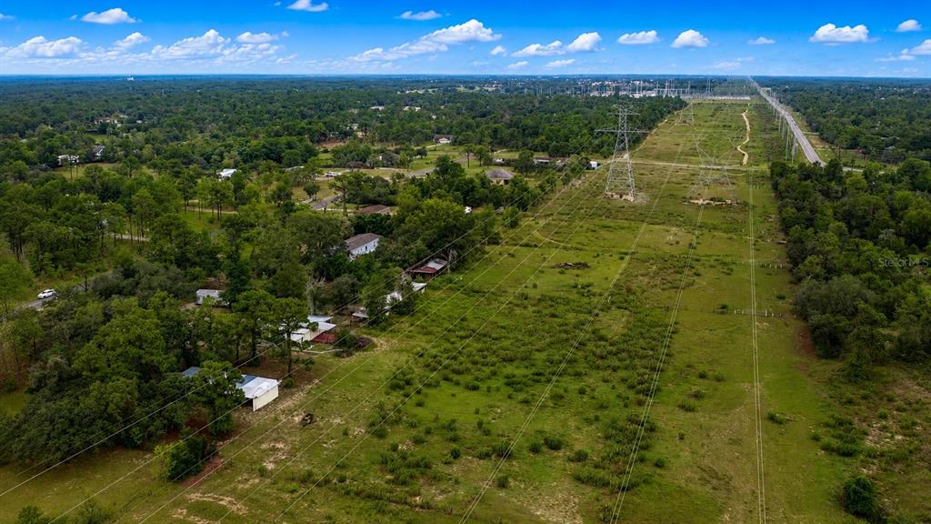 An aerial view shows a large grassy field with power lines and nearby residential homes — 11189 SALOME STREET, BROOKSVILLE, FL
