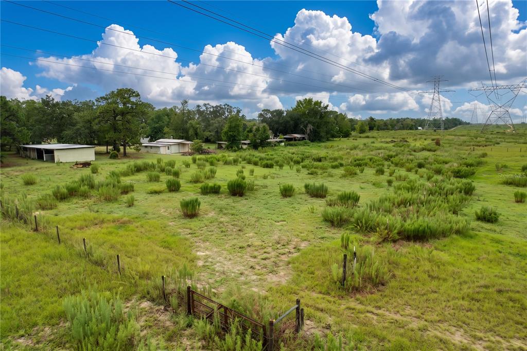 An aerial view of a grassy, fenced lot with several small outbuildings and power lines — 11189 SALOME STREET, BROOKSVILLE, FL