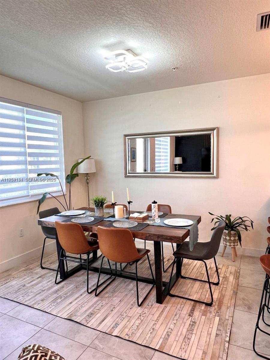 A dining room features a wooden table with mixed chairs on a patterned area rug — 6420 NW 102nd Path # 304, Doral FL 33178, DORAL, FL