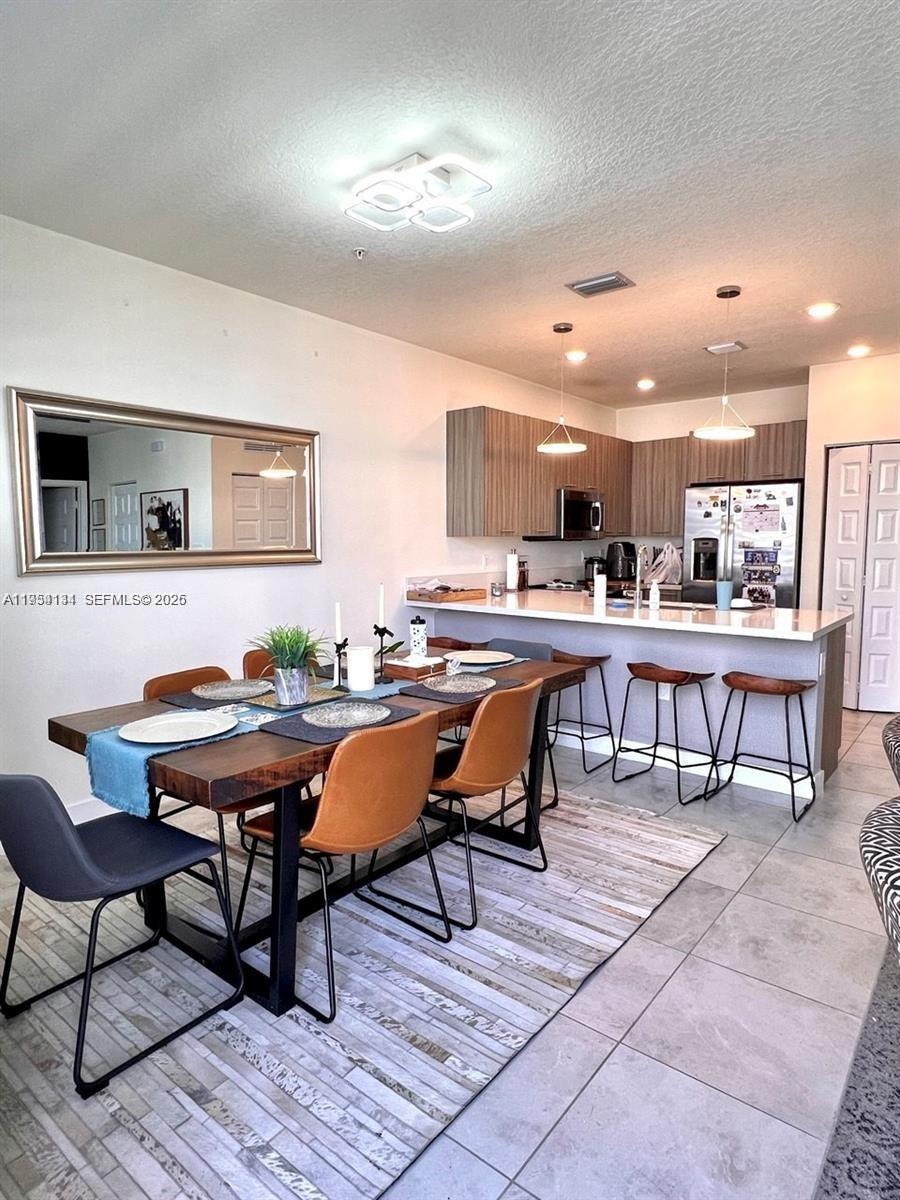A dining area with a wooden table and chairs sits adjacent to an open kitchen — 6420 NW 102nd Path # 304, Doral FL 33178, DORAL, FL