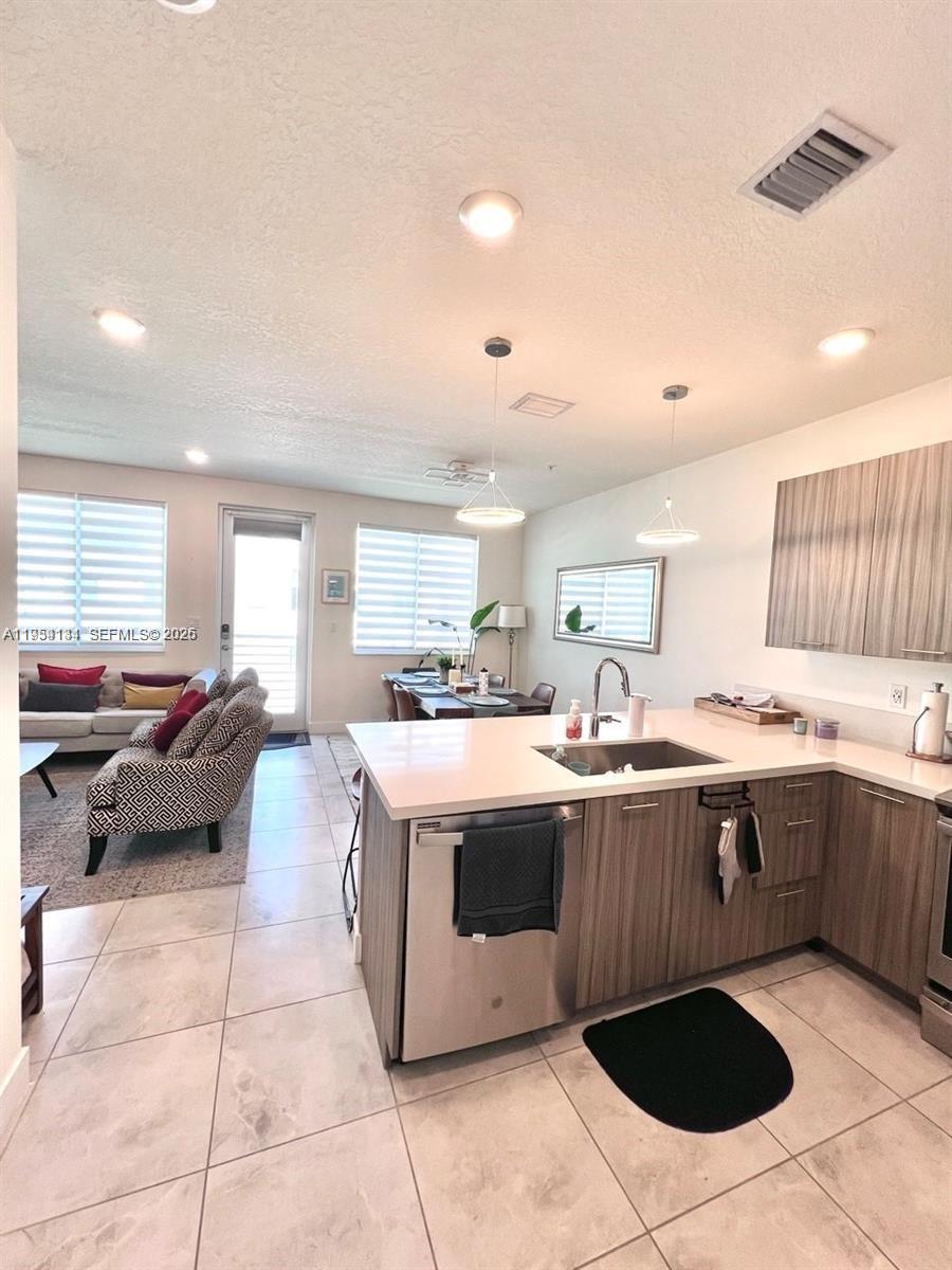 This open-concept kitchen features wood-grain cabinetry, quartz countertops, and a view of the living area — 6420 NW 102nd Path # 304, Doral FL 33178, DORAL, FL