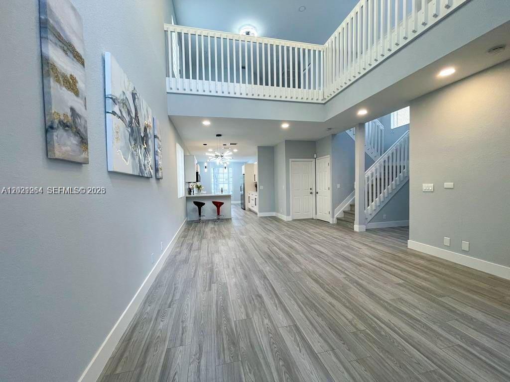 A two-story foyer features light wood-look flooring, white railings, and a view toward the kitchen — 1261 Hayes St, Hollywood FL 33019, HOLLYWOOD, FL