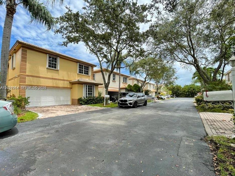 A two-story yellow townhouse with a garage and a driveway sits beside a street — 1261 Hayes St, Hollywood FL 33019, HOLLYWOOD, FL