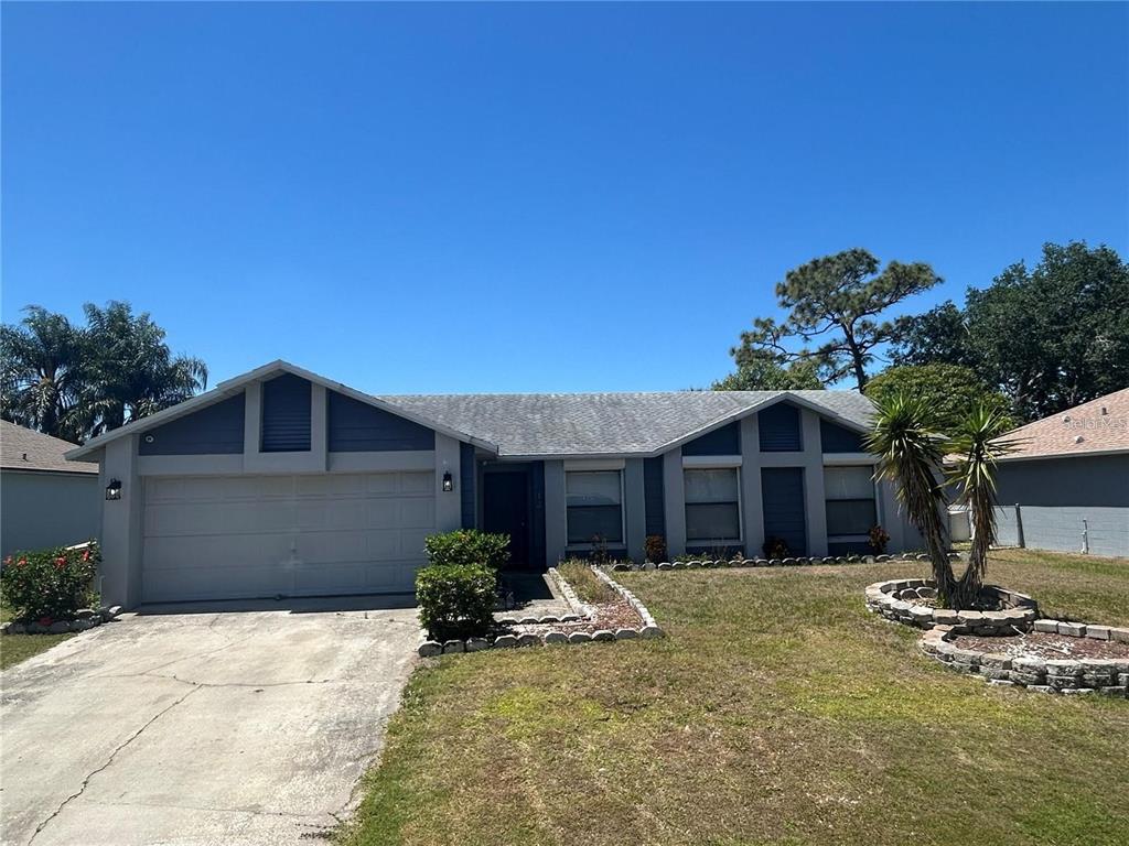 A single-story house with a two-car garage, gray siding, and a landscaped front yard — 613 BAYPORT DRIVE, KISSIMMEE, FL