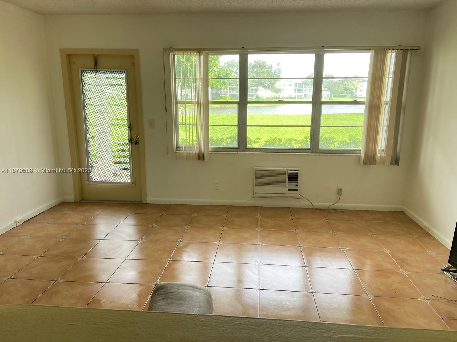 A room with light-colored walls, tiled flooring, a window air conditioner, and a glass door — 8 Fanshaw A # 8, Boca Raton FL 33434, BOCA RATON, FL