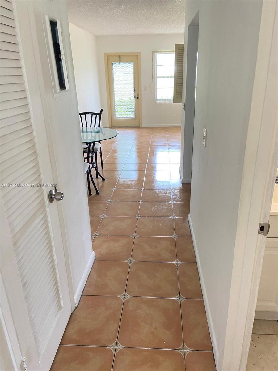 A tiled hallway leads to a dining area with a glass table and a back door — 8 Fanshaw A # 8, Boca Raton FL 33434, BOCA RATON, FL