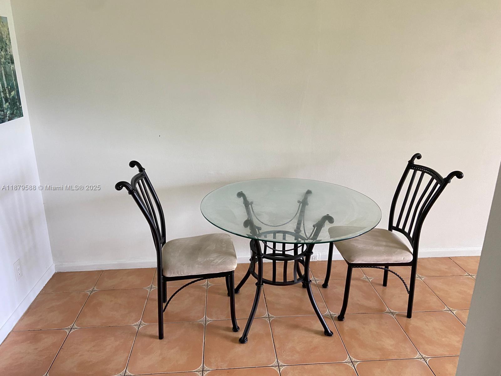 A round glass-top dining table with two chairs sits on a tiled floor — 8 Fanshaw A # 8, Boca Raton FL 33434, BOCA RATON, FL