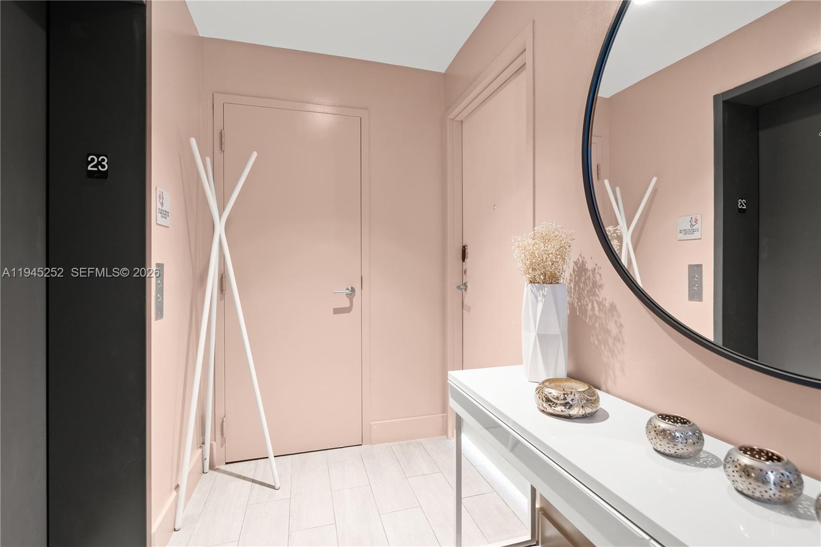 A hallway features pink walls, a white console table, a round mirror, and a coat rack — 2900 NE 7th Ave # 2309, Miami FL 33137, MIAMI, FL