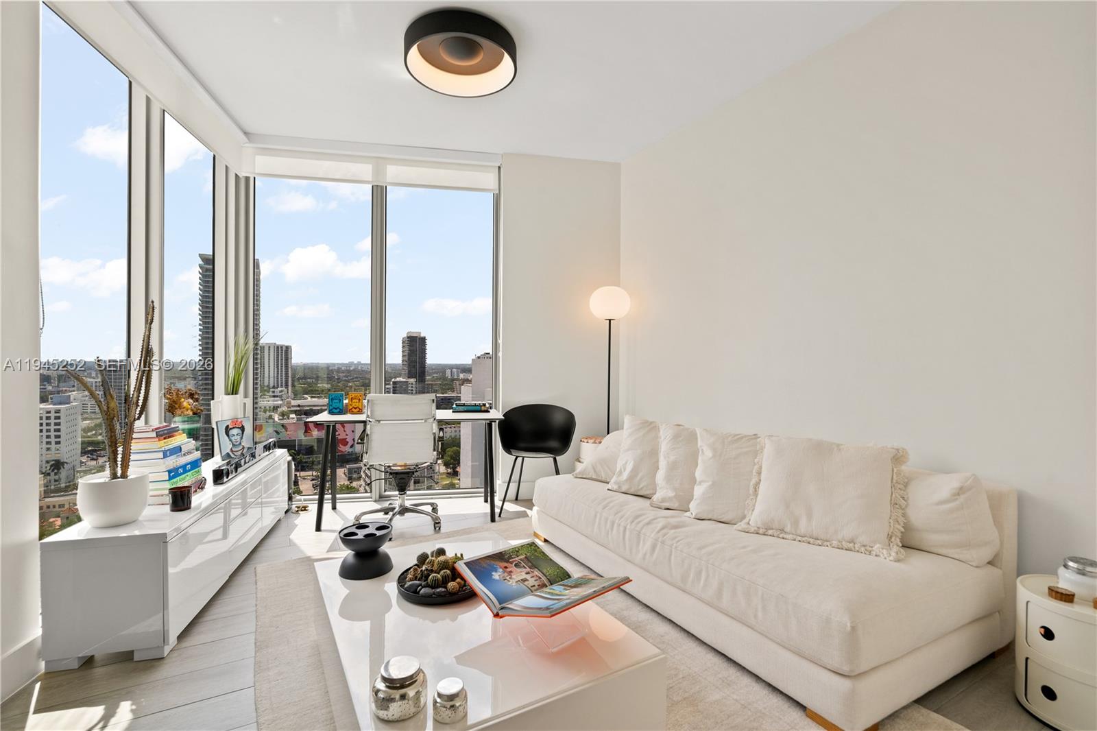 A modern living room features a white sofa, a coffee table, and floor-to-ceiling city views — 2900 NE 7th Ave # 2309, Miami FL 33137, MIAMI, FL
