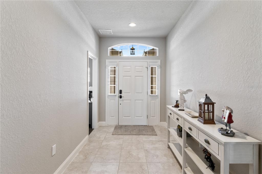 A bright entryway features a white front door, tiled flooring, and a long console table — 117 WALKERS POINT DRIVE, AUBURNDALE, FL