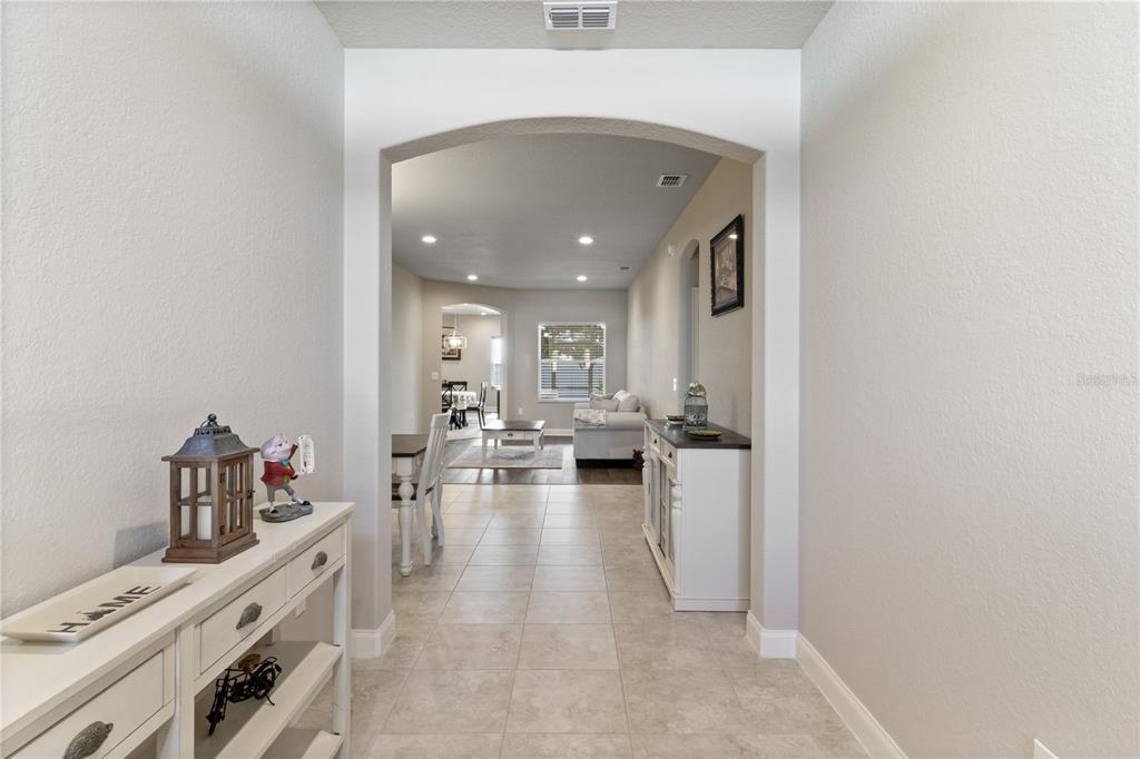 A dining area features a wooden table with white chairs, a chandelier, and tile flooring — 117 WALKERS POINT DRIVE, AUBURNDALE, FL