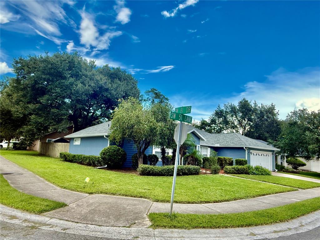 A blue single-story house with a green lawn and a street sign in the foreground — 8032 SW 51ST LANE, GAINESVILLE, FL
