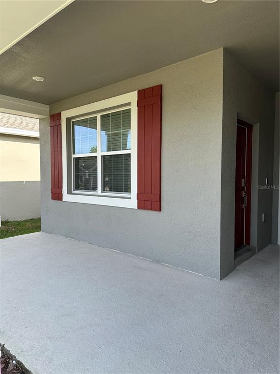 A covered porch features a window with red shutters and a red front door — 4162 BABBLING BROOK WAY UNIT B, KISSIMMEE, FL