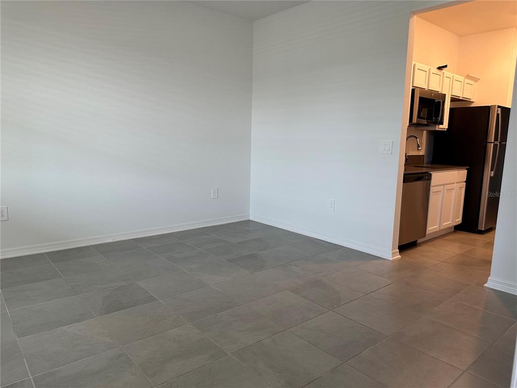 A dining area with gray tile floors opens into a kitchen with white cabinets — 4162 BABBLING BROOK WAY UNIT B, KISSIMMEE, FL