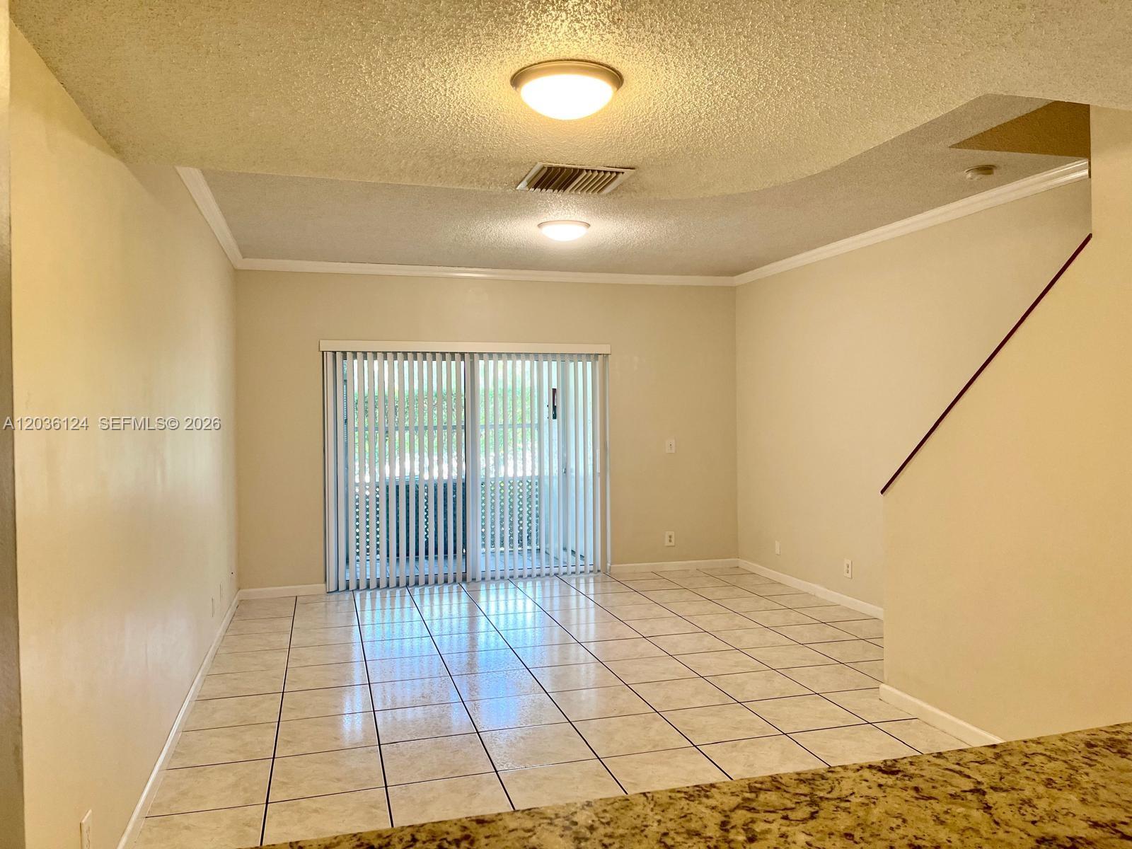 A room with light-colored tile flooring, beige walls, and a sliding glass door — WESTON, FL