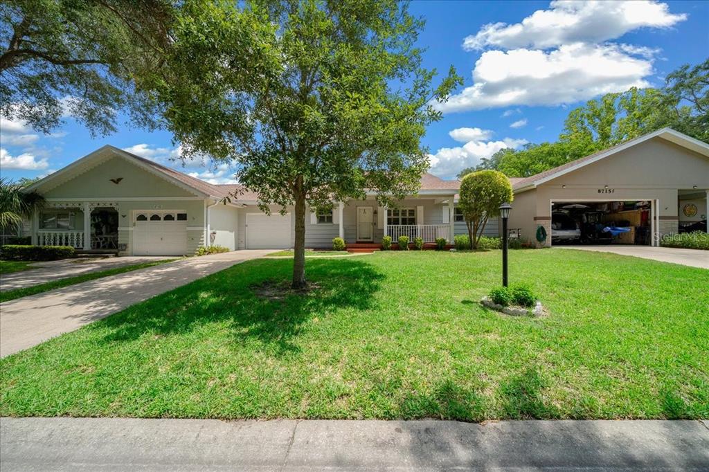 A single-story house with two garages, a large front lawn, and a central tree — 8715 SW 97TH STREET UNIT E, OCALA, FL