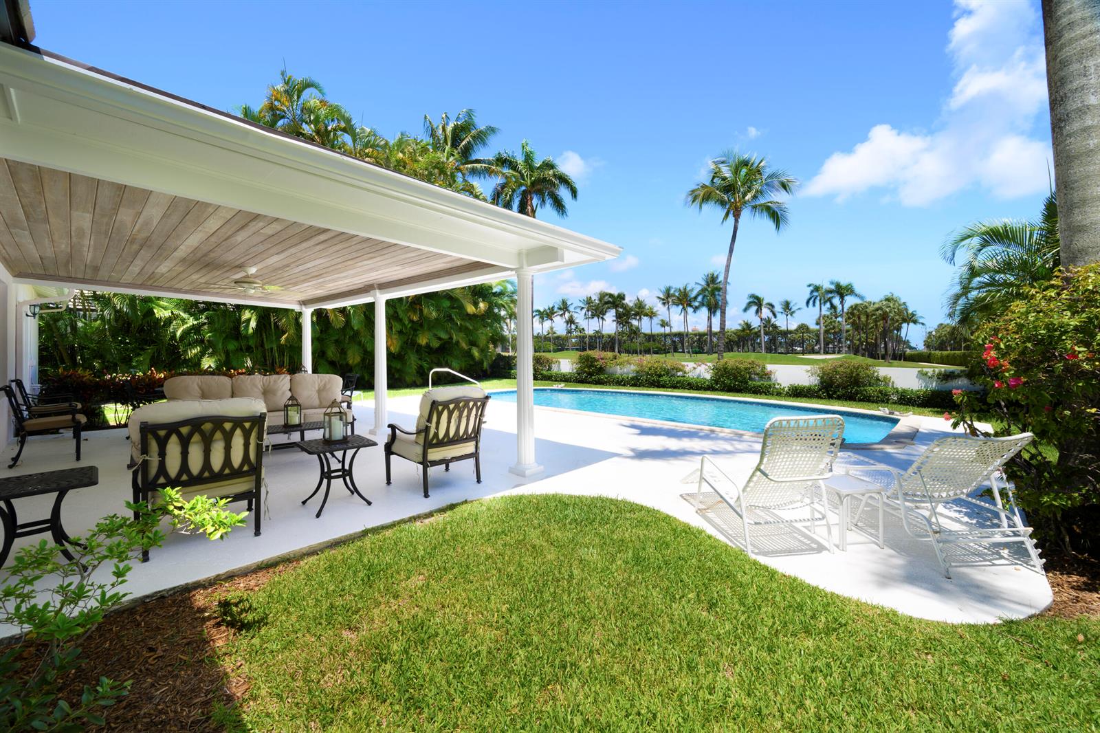 A covered patio with outdoor furniture overlooks a swimming pool and a grassy backyard — 201 Pendleton Avenue, Palm Beach FL 33480, PALM BEACH, FL