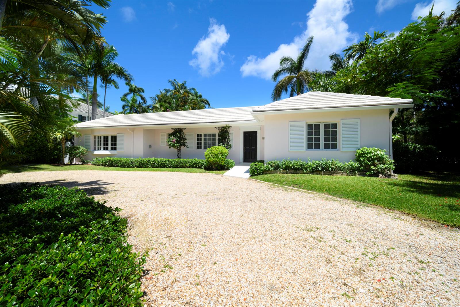 A single-story light-colored house with a gravel driveway and palm trees under a blue sky — 201 Pendleton Avenue, Palm Beach FL 33480, PALM BEACH, FL