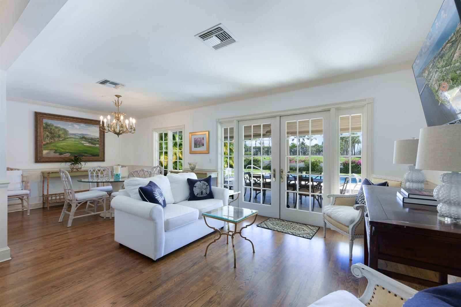 A bright living and dining area features white furniture, hardwood floors, and glass patio doors — 201 Pendleton Avenue, Palm Beach FL 33480, PALM BEACH, FL