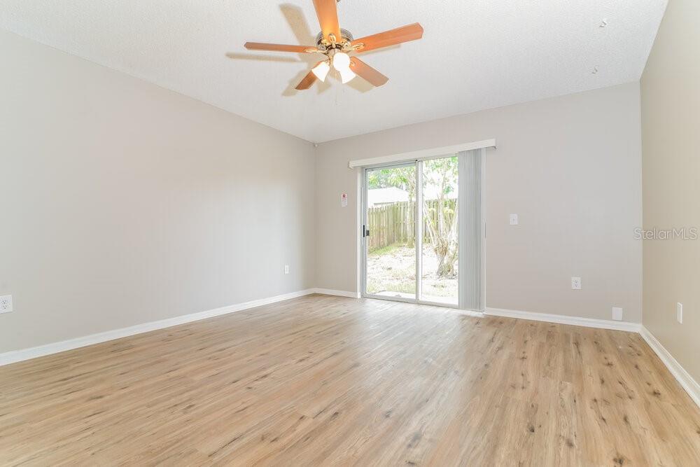 An empty room with light wood-look flooring, a ceiling fan, and sliding glass doors — 1064 REMINGTON AVENUE, EUSTIS, FL