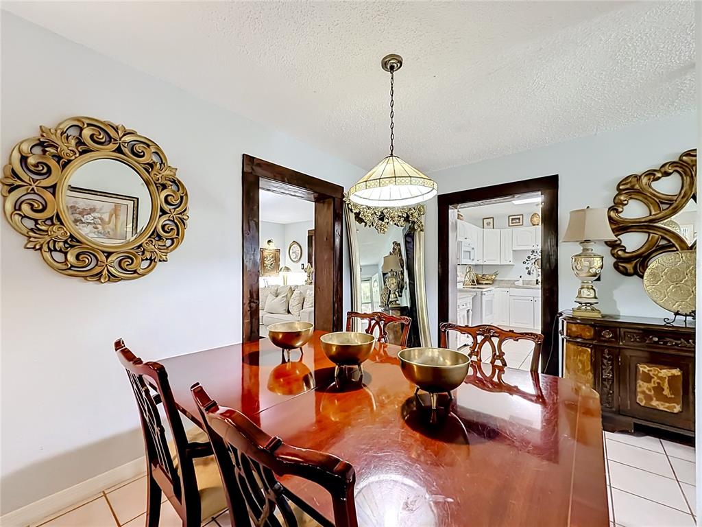A dining room with a wooden table, chairs, a pendant light, and tiled flooring — 2705 ARC DRIVE, ORLANDO, FL