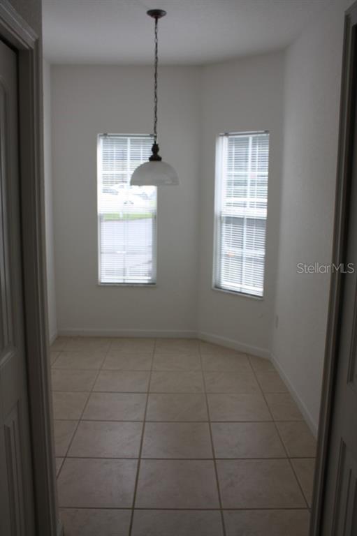 A small dining nook with tile flooring, two windows, and a hanging pendant light fixture — 2935 NE 7TH STREET UNIT 207, OCALA, FL