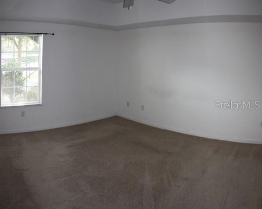 A spacious, empty bedroom features beige carpeting, white walls, and a single window — 2935 NE 7TH STREET UNIT 207, OCALA, FL