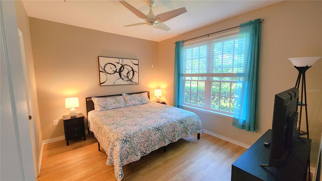 A bedroom features a bed with a patterned quilt, two nightstands, and a ceiling fan — 4106 CENTRAL SARASOTA PARKWAY UNIT 1018, SARASOTA, FL