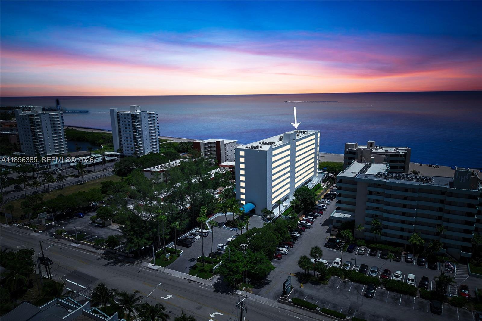 An aerial view shows a multi-story apartment building near the ocean at sunset — 1500 N Ocean Blvd # 801, Pompano Beach FL 33062, POMPANO BEACH, FL