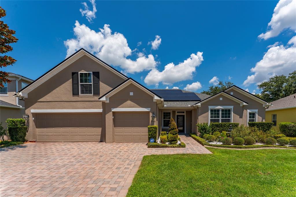 A tan single-story house with a paved driveway, solar panels, and a three-car garage — 2260 PICKFORD CIRCLE, APOPKA, FL