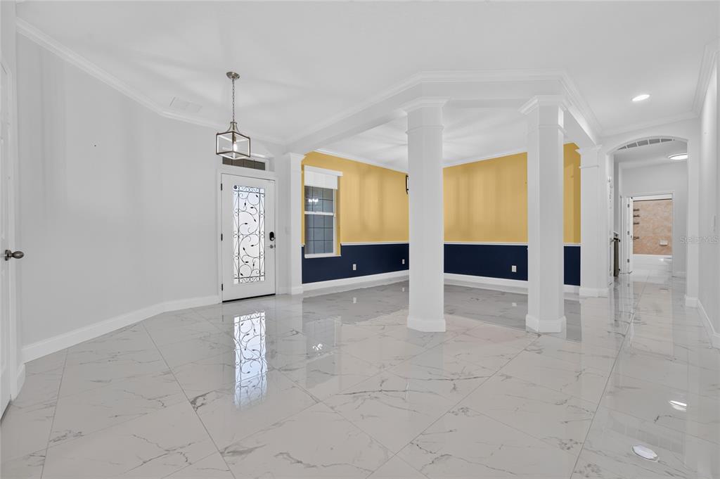 An entryway with white marble-look tile flooring, white columns, and yellow and navy blue walls — 2260 PICKFORD CIRCLE, APOPKA, FL