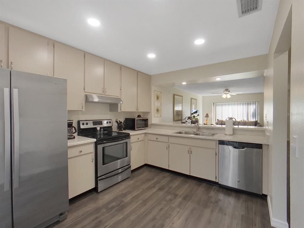 A kitchen with beige cabinets, stainless steel appliances, and wood-look flooring — 7805 AMBERLEA COURT, TEMPLE TERRACE, FL