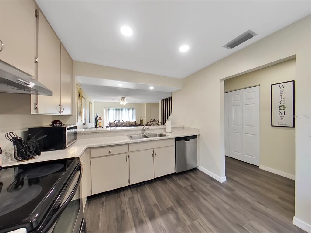 A kitchen features light-colored cabinets, stainless steel appliances, and wood-look flooring — 7805 AMBERLEA COURT, TEMPLE TERRACE, FL