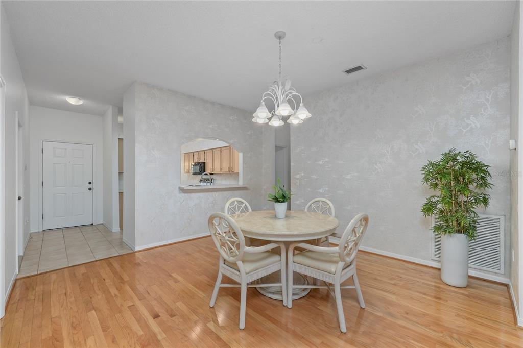 A dining area features a round table, four chairs, a chandelier, and light wood flooring — 3511 TEALWOOD CIRCLE, PALM HARBOR, FL