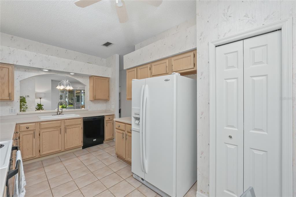 A kitchen features light wood cabinets, a white refrigerator, a black dishwasher, and tiled floors — 3511 TEALWOOD CIRCLE, PALM HARBOR, FL