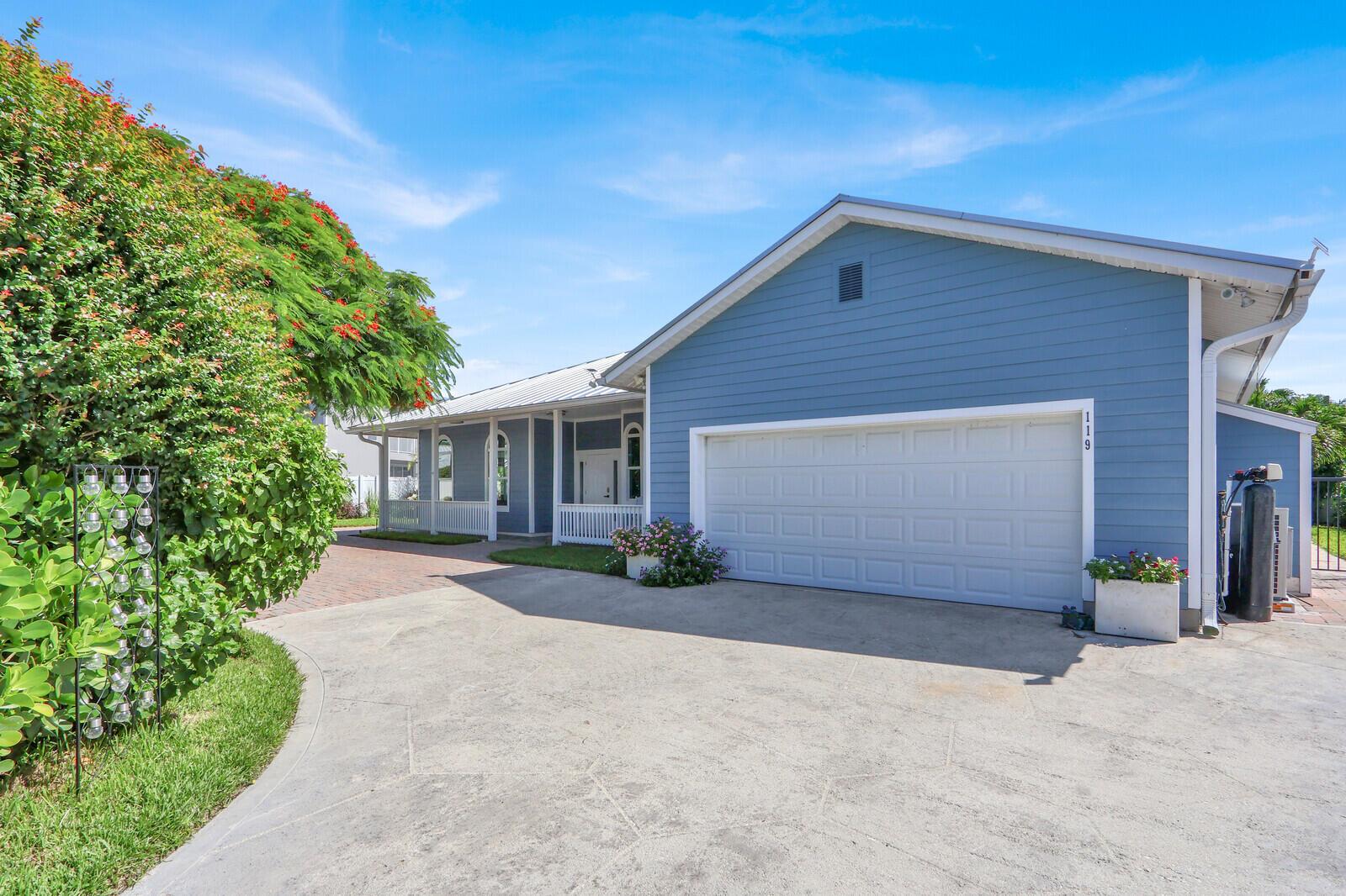 A blue house with a white garage door, a covered porch, and a concrete driveway — 119 Faith Way, Jupiter FL 33458, JUPITER, FL