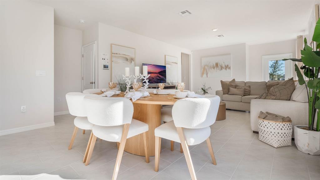 A dining area with a round wooden table and white chairs sits before a living room — 4417 LAKE FOX DRIVE, LAKELAND, FL