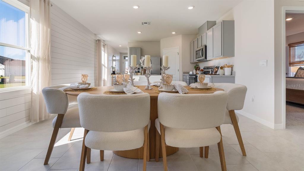A dining area features a round wooden table, four upholstered chairs, and shiplap wall paneling — 4417 LAKE FOX DRIVE, LAKELAND, FL