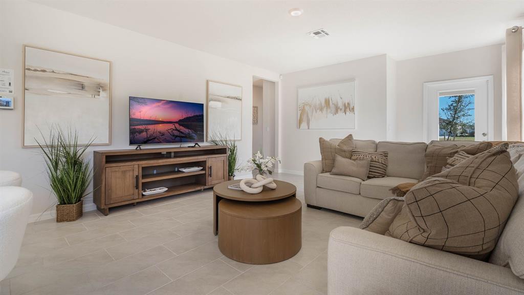 A living room features a television on a wooden console, a sectional sofa, and tile flooring — 4417 LAKE FOX DRIVE, LAKELAND, FL