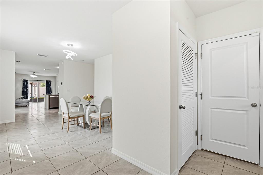 A tiled entryway leads to a dining area with a glass table and open kitchen — 2839 MAIDEN GRASS ISLE, WESLEY CHAPEL, FL