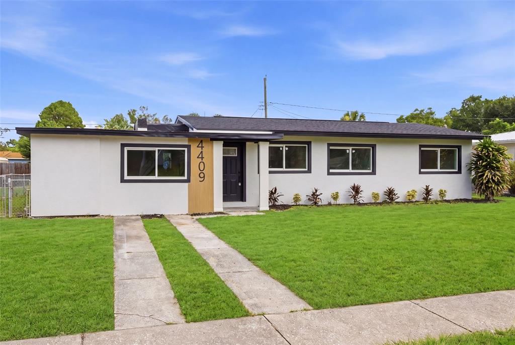 A single-story house with a white exterior, dark trim, and a concrete driveway — 4409 W WYOMING AVENUE, TAMPA, FL