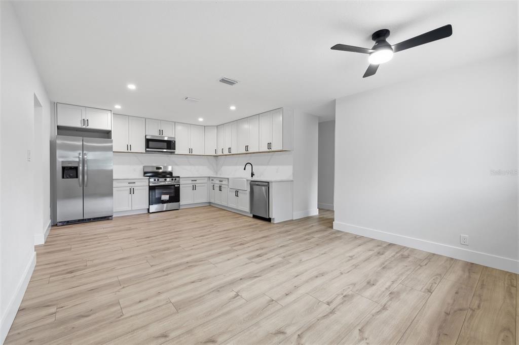 A kitchen with white cabinets, stainless steel appliances, and light wood-look flooring — 4409 W WYOMING AVENUE, TAMPA, FL