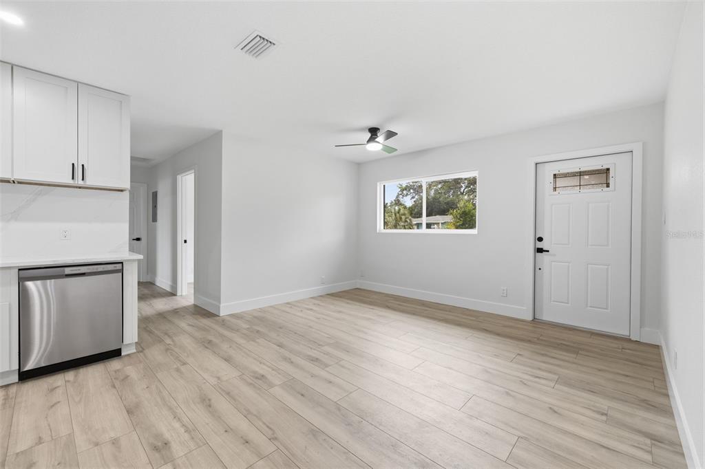 A living room features light wood flooring, a sectional sofa, a coffee table, and kitchen cabinetry — 4409 W WYOMING AVENUE, TAMPA, FL