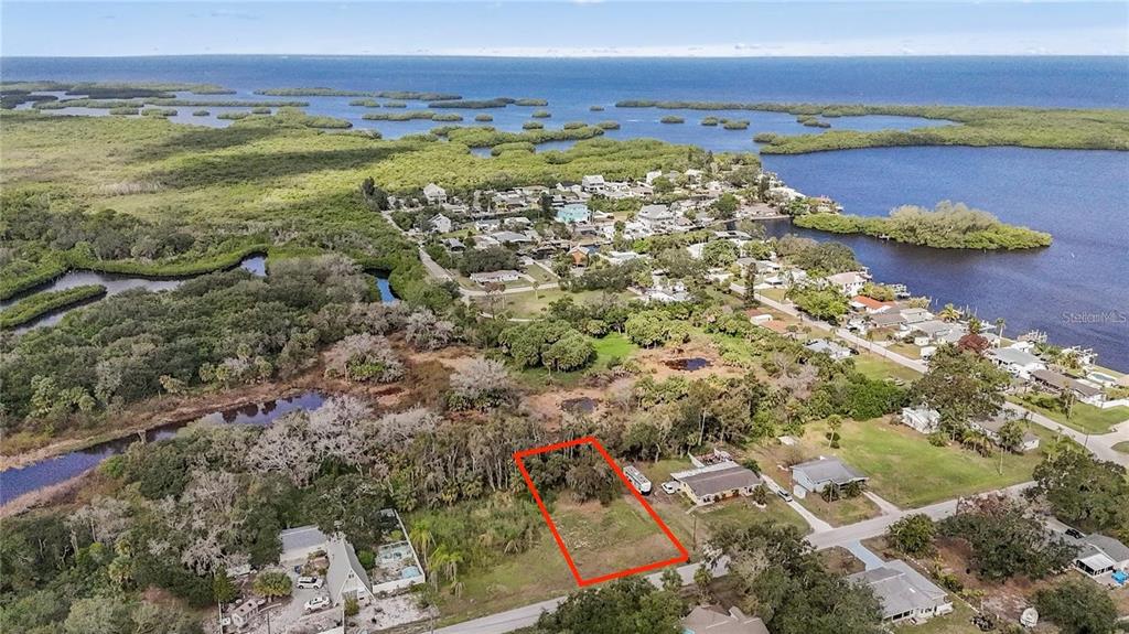 An aerial view shows a vacant rectangular lot outlined in red near a coastal neighborhood — 1115 CANAL STREET, RUSKIN, FL