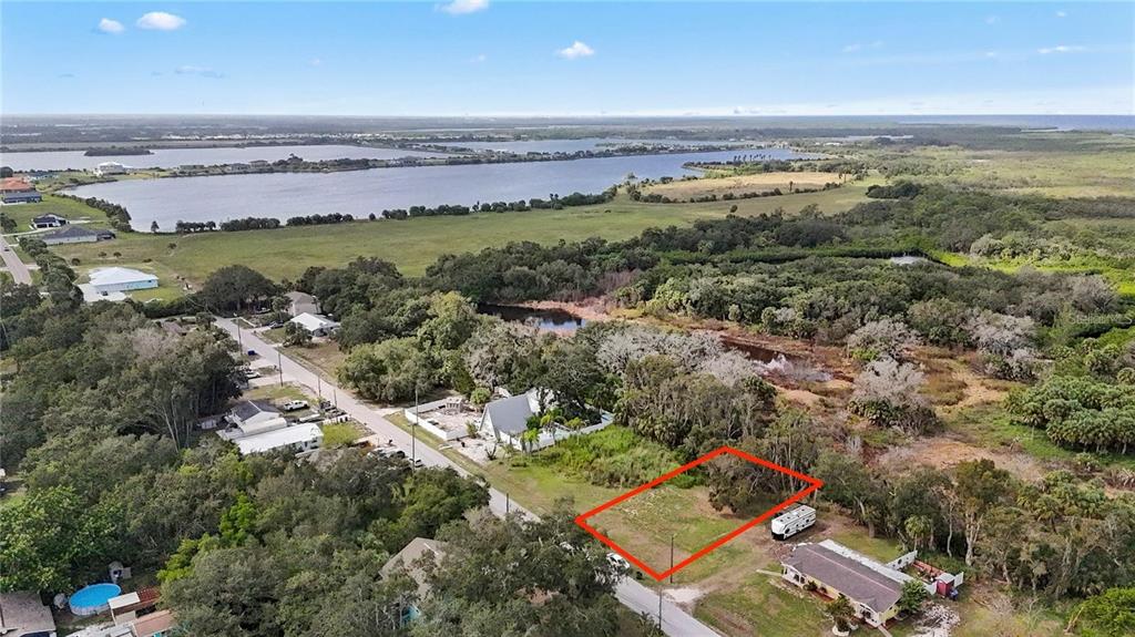 An aerial view shows a vacant rectangular lot outlined in red next to a house — 1115 CANAL STREET, RUSKIN, FL