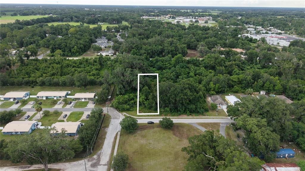 An aerial view shows a rectangular plot of land highlighted in white amidst dense vegetation — SW 2ND AVENUE, CHIEFLAND, FL