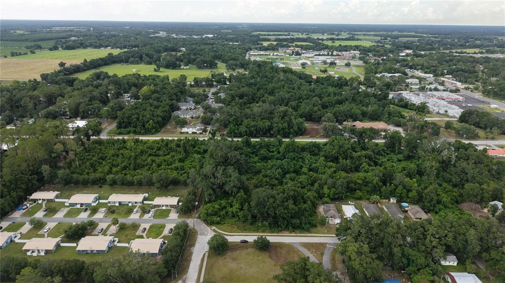 An aerial view shows a residential area with clusters of houses, dense trees, and roads — SW 2ND AVENUE, CHIEFLAND, FL
