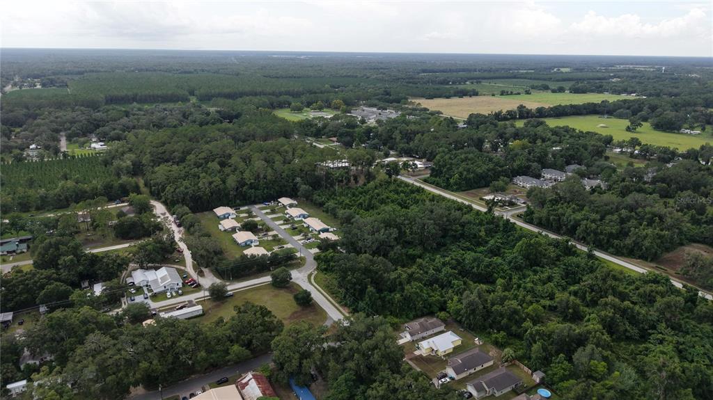 An aerial view shows a residential neighborhood surrounded by dense forest and open fields — SW 2ND AVENUE, CHIEFLAND, FL